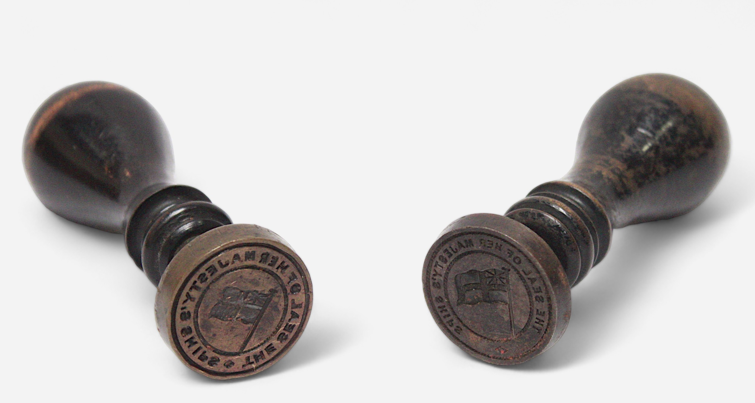 Two wooden and brass wax seal stamps, stamping the phrase ‘The Seal of Her Majesty’s Ships’ with