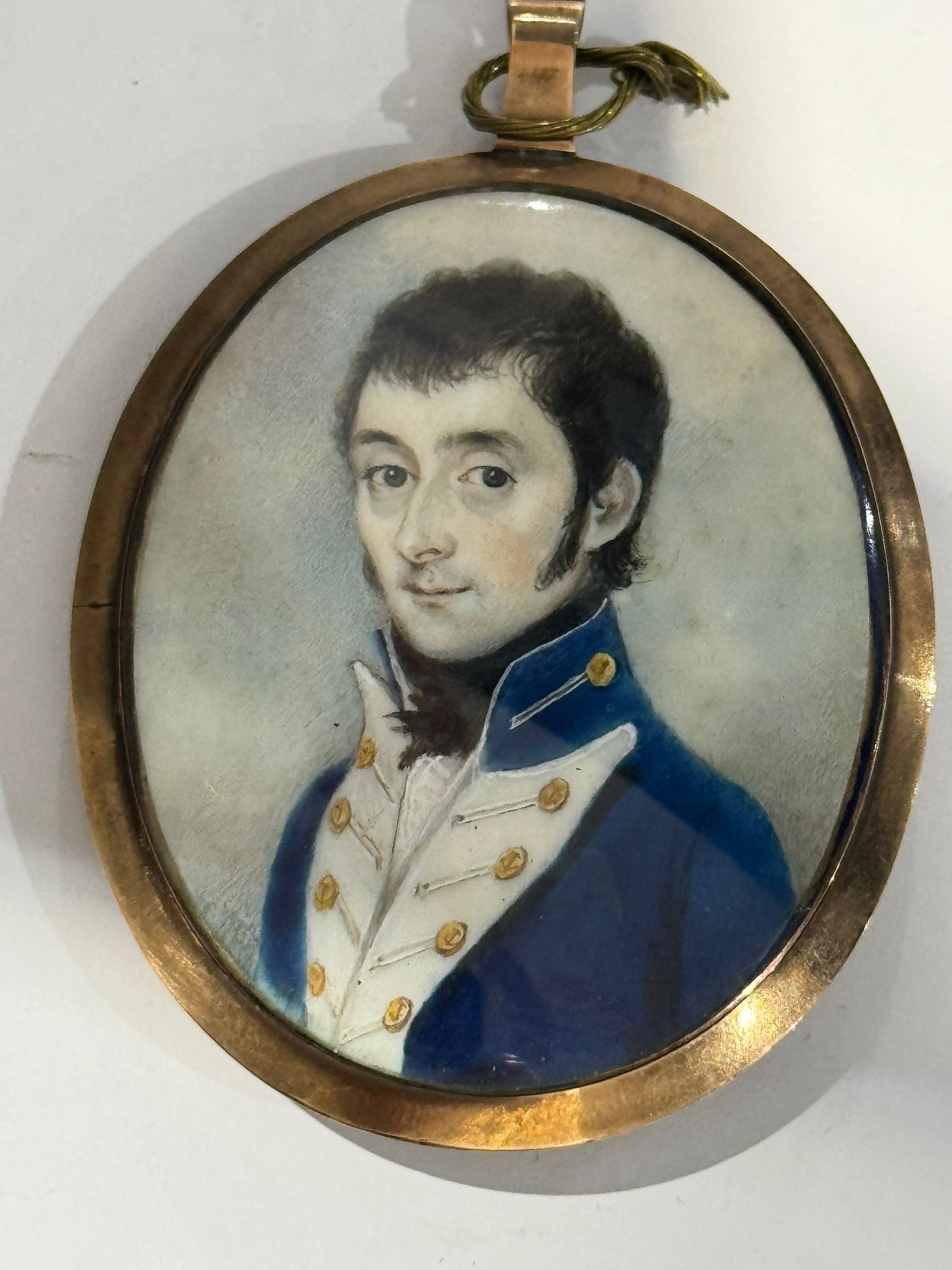An early 19th century oval locket-back portrait miniature of a Junior Naval officer, with dark brown