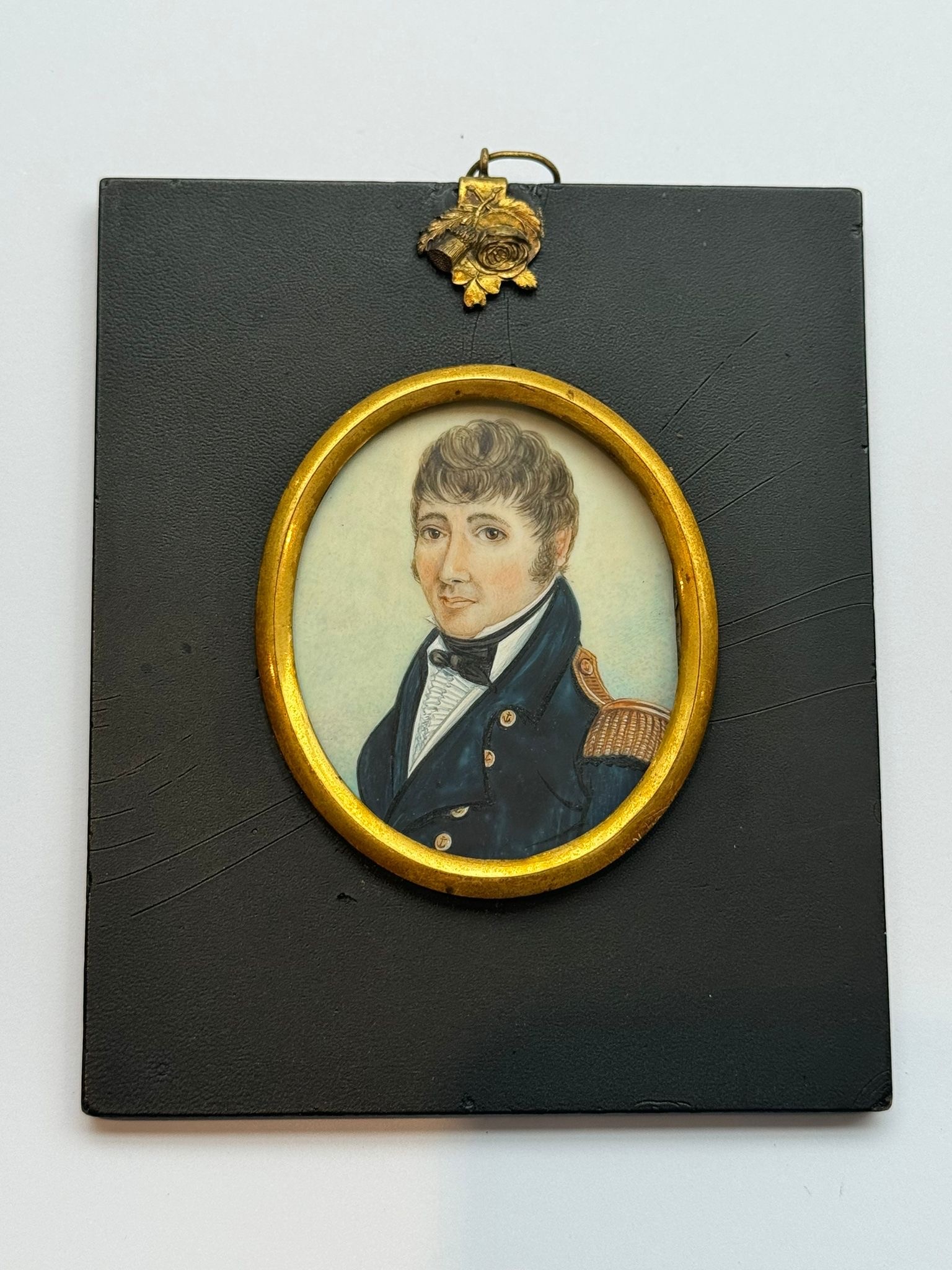 A 19th century oval portrait miniature of a naval officer, with brown hair, body turned half