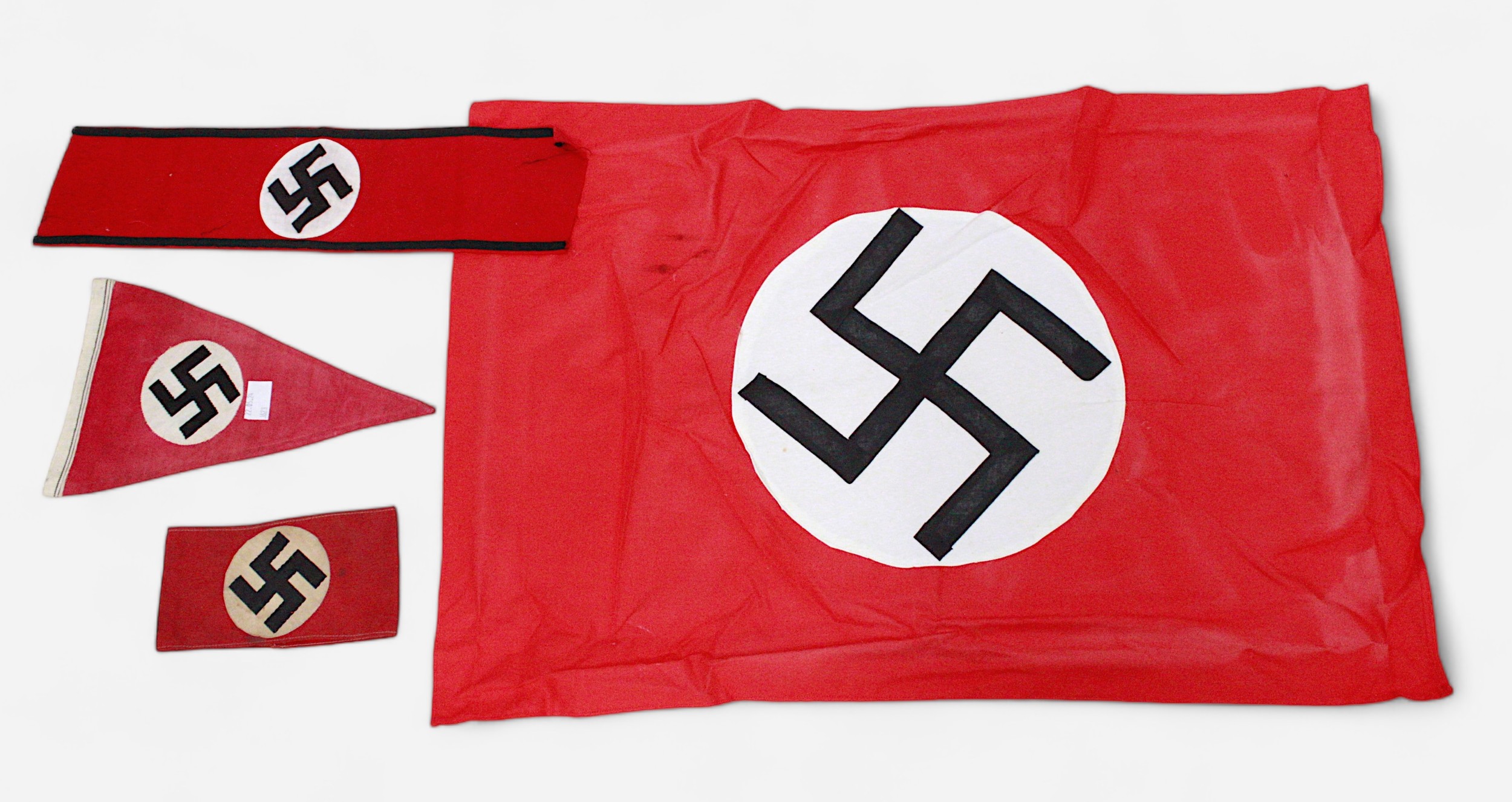 A WWII German Third Reich Swastika pennant, together with an armband, another felt armband and flag.