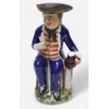 A Prattware ‘Sailor’ toby jug, c1810, with blue frock coat and matching britches, a long tobacco