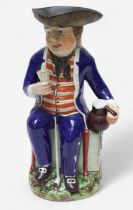 A Prattware ‘Sailor’ toby jug, c1810, with blue frock coat and matching britches, a long tobacco