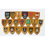 Approximately thirty various military crests, mounted and carved on wooden plaques, including The