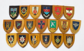 Approximately thirty various military crests, mounted and carved on wooden plaques, including The