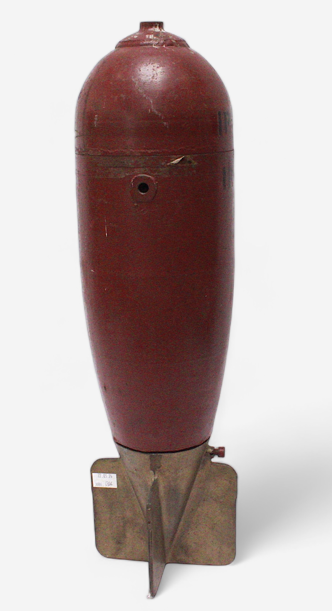 A large WWII aerial 'Practice Bomb,' outer casing painted red, marked ‘IP42’, with brass four-