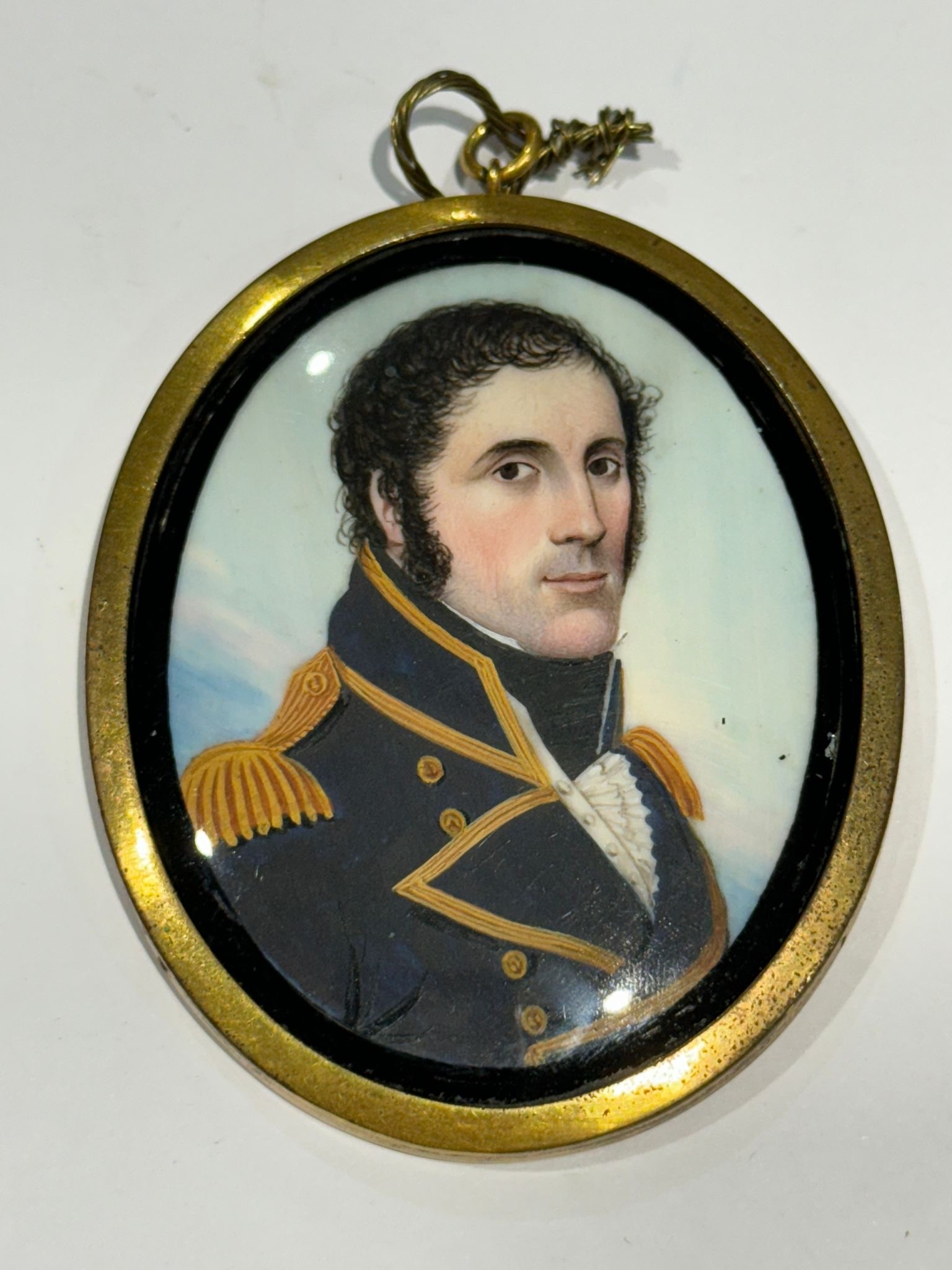 A Mid-19th century oval portrait miniature of a senior Naval officer, with black curly hair and