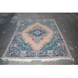 A Border patterned and fringed rug having floral detail in green and cream and terracotta.