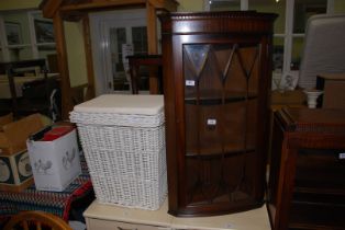 A wicker linen basket and a Mahogany framed wall-hanging corner cabinet, 22" x 39" high.