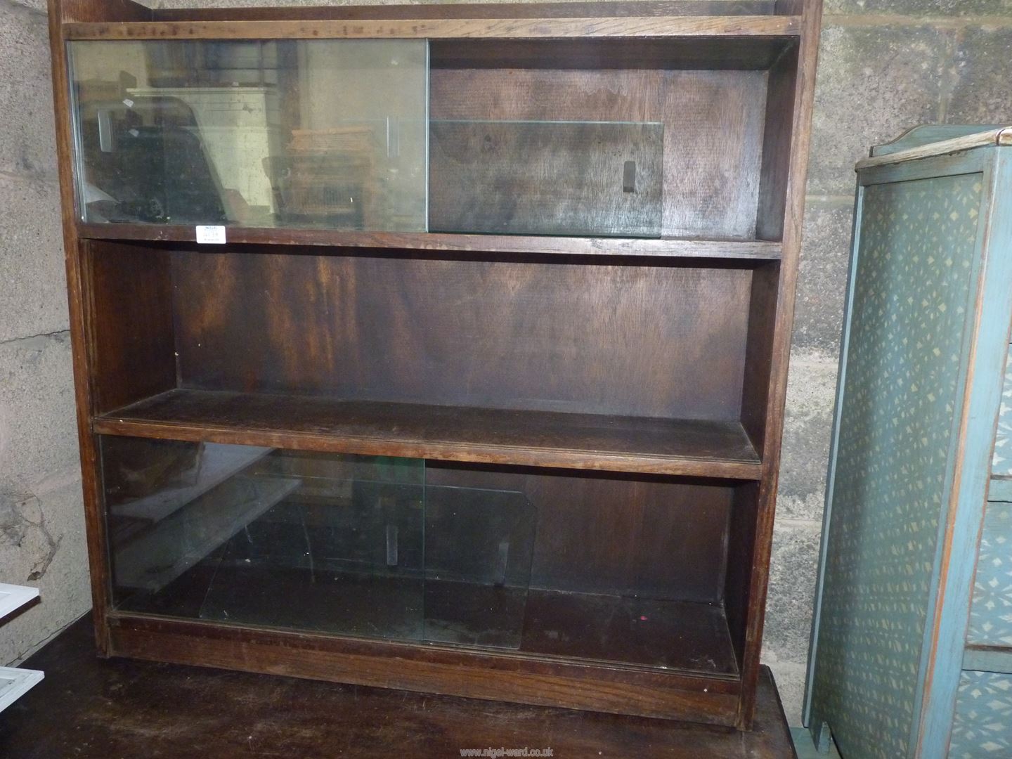 A wooden shelving unit with sliding top doors 3' wide x 8 1/2" x 3' high.