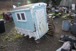 A wooden playhouse on a garden trolley, 48'' long x 32'' wide x 48'' high.