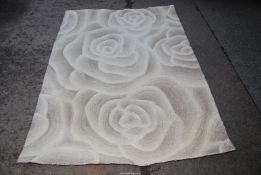 A cream rug with a rose pattern . 137cm x 195 cm.