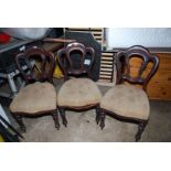 Three dining chairs with upholstered seats.