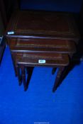 A Mahogany nest of three tables with leather inserts.