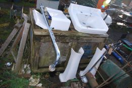 A sink, water cistern, chrome pipe and two pedestals.