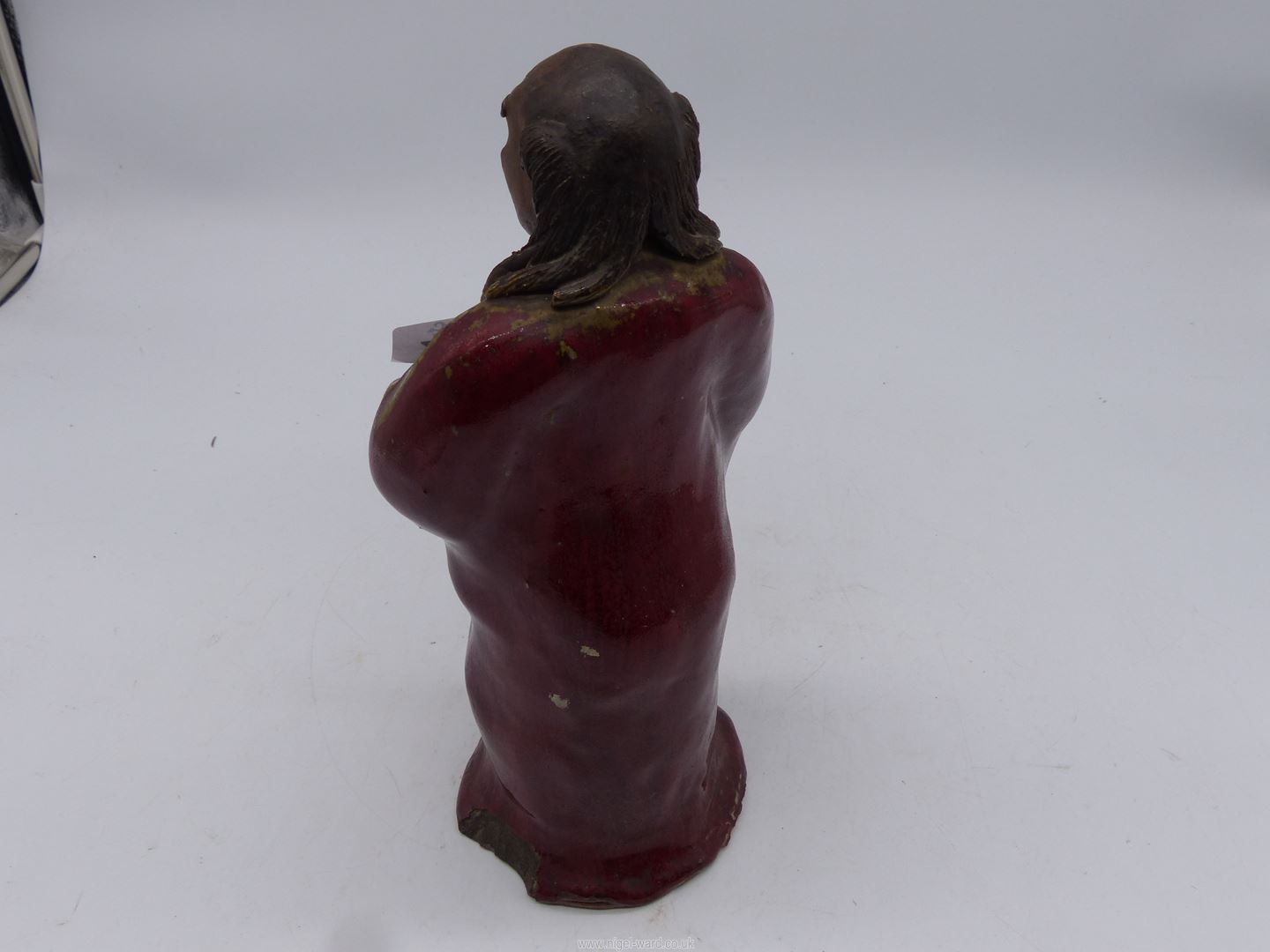 A Japanese red glazed stoneware figure of an Immortal holding a shoe, 11 1/4" tall. - Image 2 of 3