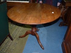An Oak birdcage type snap-top circular Table having a turned pillar and three swept feet,