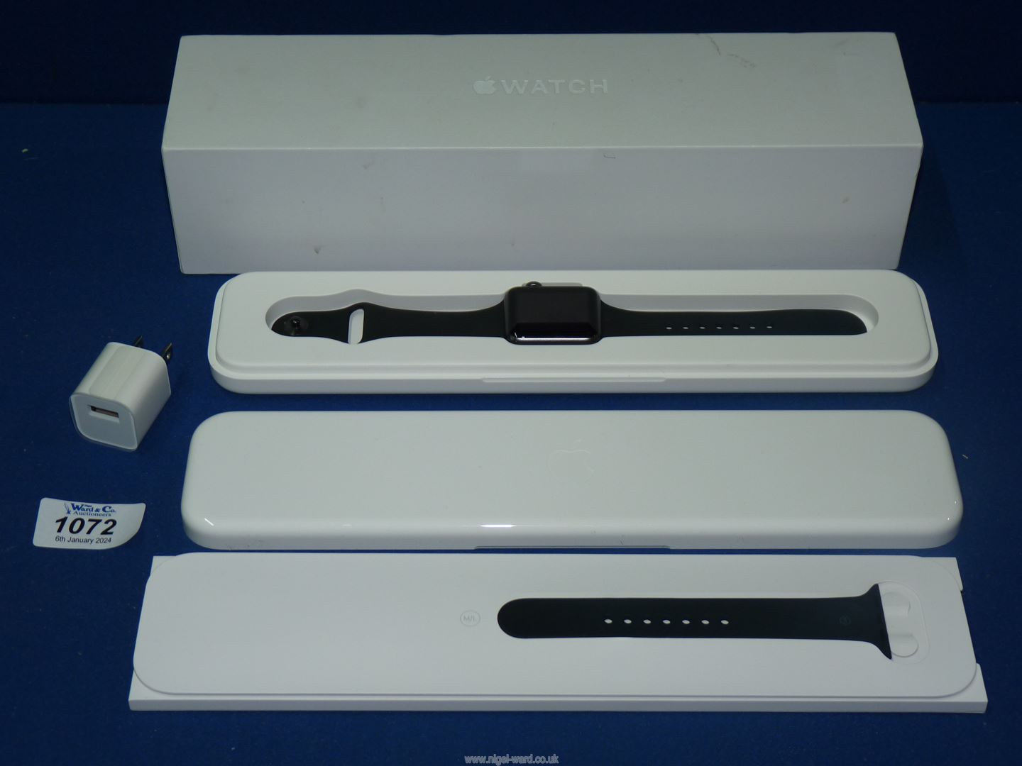 A black Apple watch sport 7000 series, with charging pin, boxed and cased.