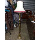 A brass based Standard Lamp with cream and maroon shade.