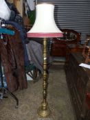 A brass based Standard Lamp with cream and maroon shade.
