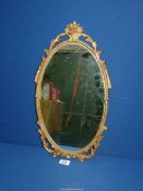 An ornately framed oval wall mirror, 19 3/4'' high x 10 1/2'' wide.