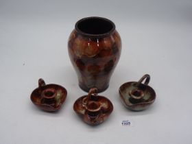 Four Ewenny Pottery pieces including three chamber sticks and a vase.