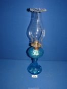 A blue glass oil lamp with fluted chimney, 17" tall.