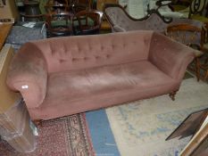 A beige buttoned upholstered Chesterfield type Settee on turned legs.
