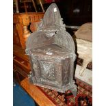 A carved Black Forest Oak wall hanging Corner Cupboard, the door featuring a fearsome carved face,