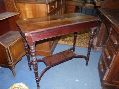 An Edwardian satinwood Table standing on turned legs united by a lower shelf,