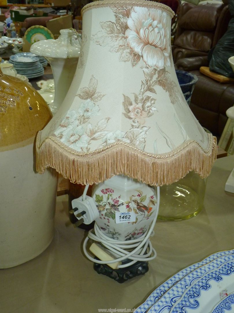 A pretty china lamp base in white ground with birds and floral pattern comes with floral fringed