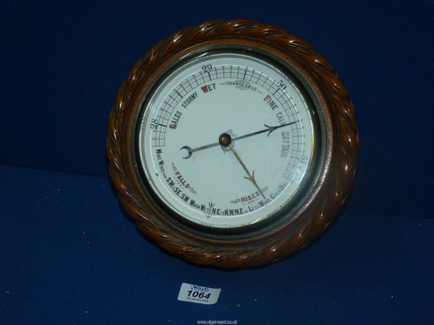 A circular oak framed aneroid Barometer with carved rope surround, 9 1/2'' diameter.