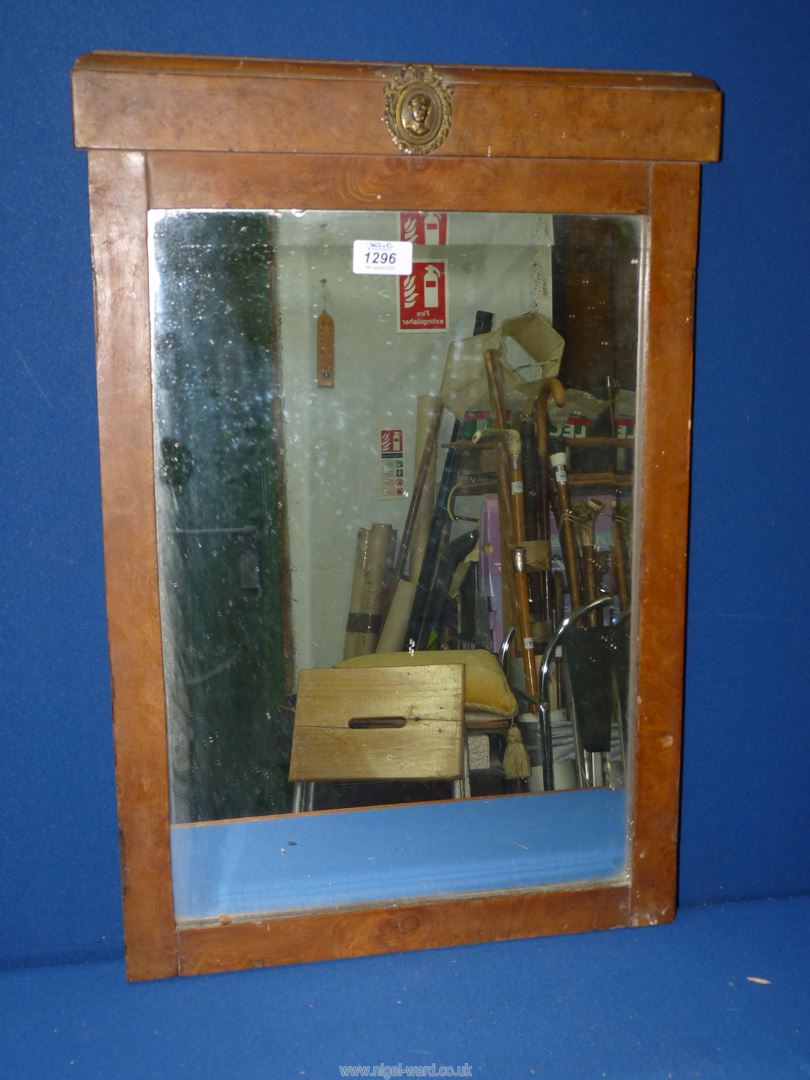 A Walnut type framed bevel plated mirror, with metal plaque to pediment depicting face of a lady,