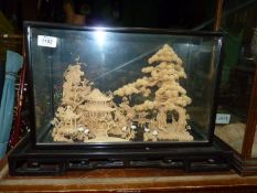 An oriental Cork diorama with house and surrounding trees in a glass case,