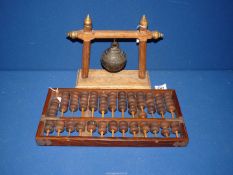 A bronze Crotal bell of some age on a frame, 9" long, plus a mahogany frame Abacus mounted in brass,