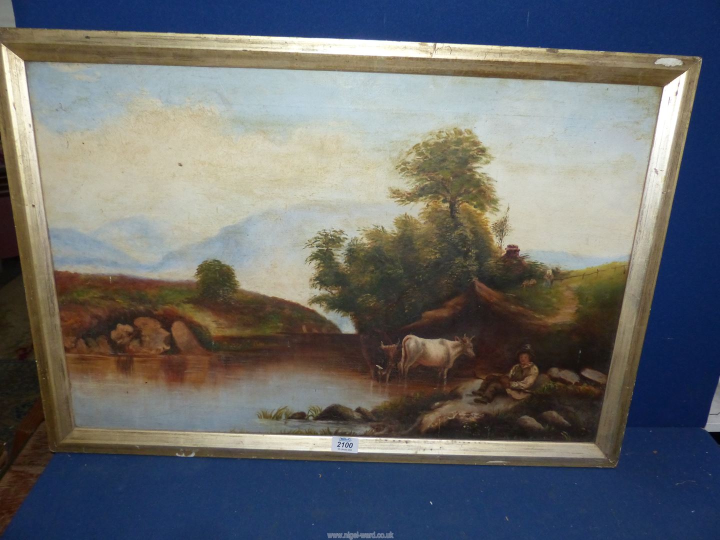 A framed Oil on canvas of cattle drinking from a river as a young cattle herder sits beneath the