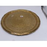 A large brass charger with pierced rims and Eastern style decoration, some bends to the rim,