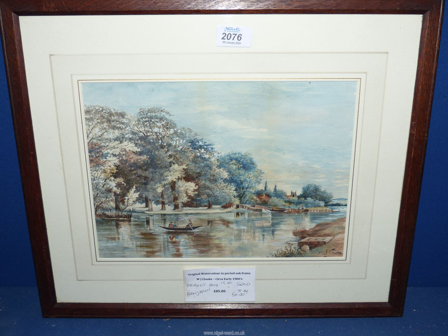 An oak framed Watercolour of a river landscape with figures in a boat and church in the distance,