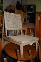 A low limed wood Chair with caned back and seat.