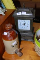 A clock and a salt glazed wine jug with tap.