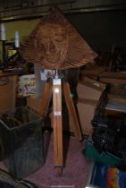 A tripod with a wood carving.