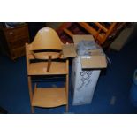 A travel cot (boxed) and a wooden feeding chair.