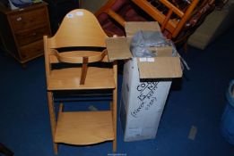 A travel cot (boxed) and a wooden feeding chair.