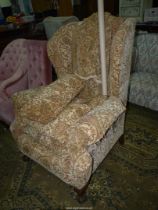 An elegant shaped wing Fireside Chair upholstered in beige ground fabric with stylised flowering