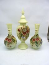 A milk glass garniture of a lidded vase and two smaller vases having floral and foliage decoration,