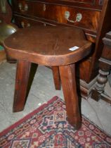 A heavy rustic "Wonderwood" darkwood Stool having shaped top and sanding on three splay feet,