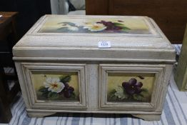 A two panelled miniature chest having recessed panels with depictions of flower blooms raised on