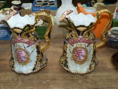 A pair of large Regency Ironstone jugs having gilded decoration and small landscape panel to both