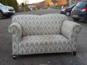 A floral upholstered two seater Settee with one drop-end.