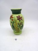 A pale green glass vase with a panel hand painted flowers to the front and darker green thick band