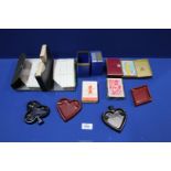 A box containing playing cards and four suit shaped ashtrays.